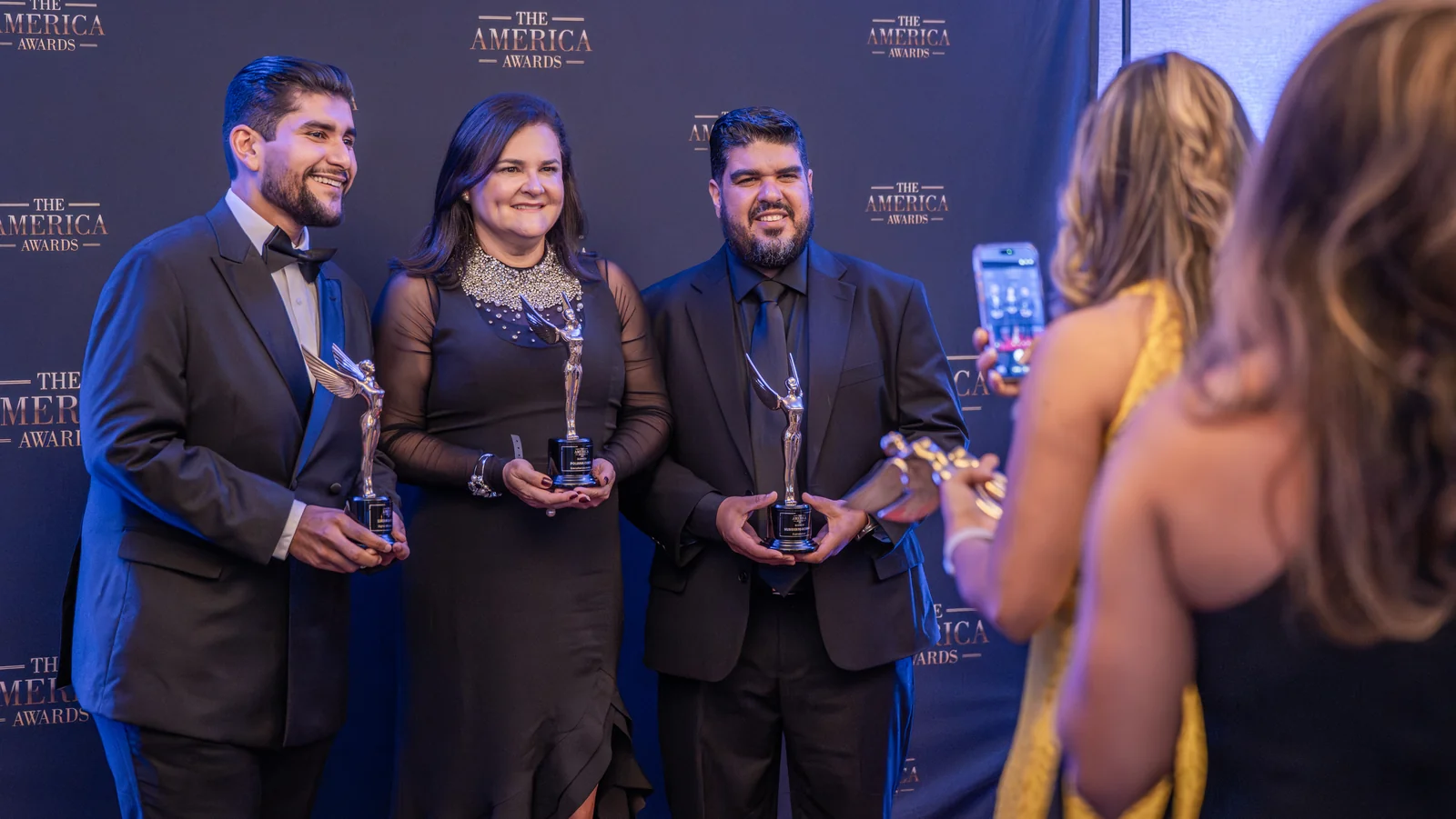 Honorees posing with their trophies on stage at The America Awards ceremony